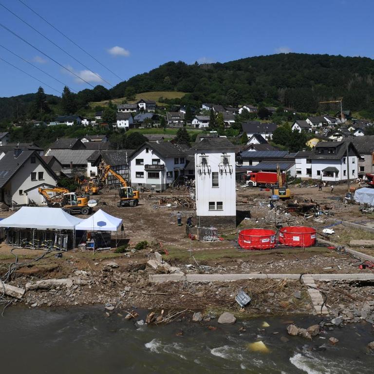 Einzelne Gebäude stehen auf schlammigem Brachland, dazwischen Zelte der Rettungskräfte
