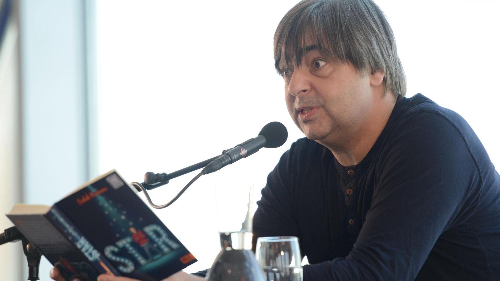 Der deutsche Autor Salah Naoura sitzt bei einer Lesung seines Buches «Star» im Rahmen des Literaturfestivals Lit.Cologne auf der Bühne. Der deutsche Autor Salah Naoura sitzt bei einer Lesung seines Buches «Star» im Rahmen des Literaturfestivals Lit.Cologne auf der Bühne.