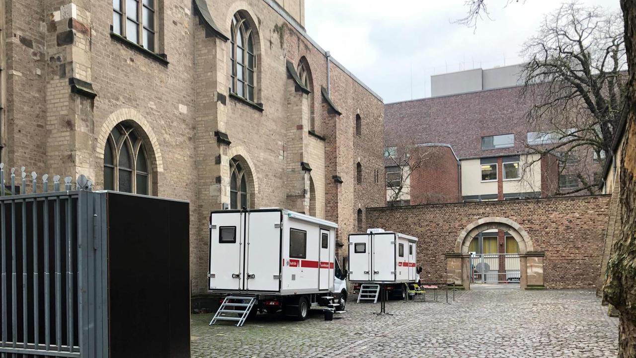 Zwei Busse des Kölner Gesundheitsamts, rot-weiß beschriftet wie Krankenwagen, stehen auf dem Platz hinter der katholischen Kirche St. Peter unweit des Neumakts. Drogensüchtige können hier hygienische Konsumräume nutzen und sauberes Spritzbesteck erhalten.