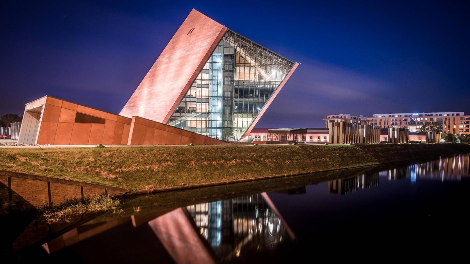 Der Museumsbau des Architekturbüro Kwadrat in Gdynia in Form eines schräg aus dem Boden ragenden und teilweise verglasten Würfels in nächtlicher Beleuchtung. Der Museumsbau des Architekturbüro Kwadrat in Gdynia in Form eines schräg aus dem Boden ragenden und teilweise verglasten Würfels in nächtlicher Beleuchtung.