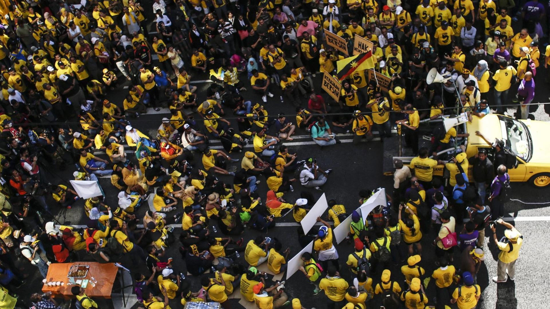 Das Luftbild zeigt einen Sitzstreik von Demonstranten in gelben Shirts in Kuala Lumpur. Sie demonstrieren gegen Premierminister Najib Razak.