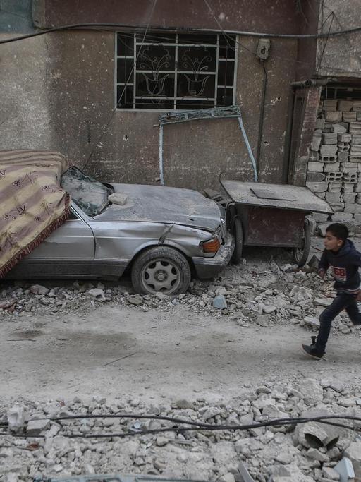 Syrien, Ost-Ghuta: Ein syrischer Junge rennt durch die Überreste von durch Luftangriffen zerstörten Häusern.