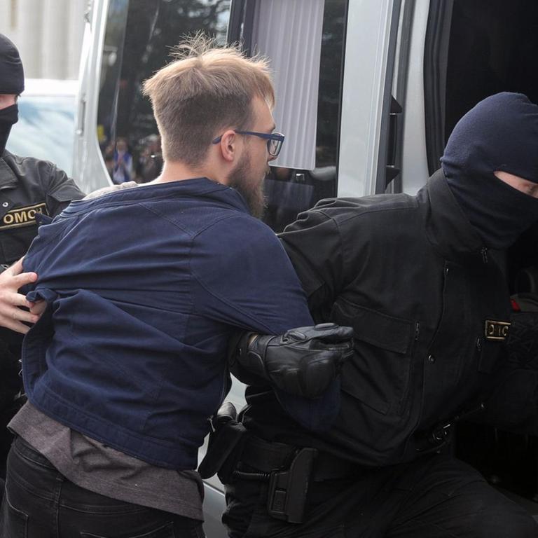 Polizeikräfte nehmen bei Protesten in Minsk einen Studenten fest und schieben ihn in einen Transporter. 