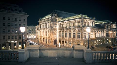 Das angestrahlte Opernhaus ist seitlich zu sehen, über einen Platz mit festlicher Beleuchtung hinweg.