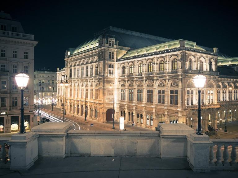 Das angestrahlte Opernhaus ist seitlich zu sehen, über einen Platz mit festlicher Beleuchtung hinweg.