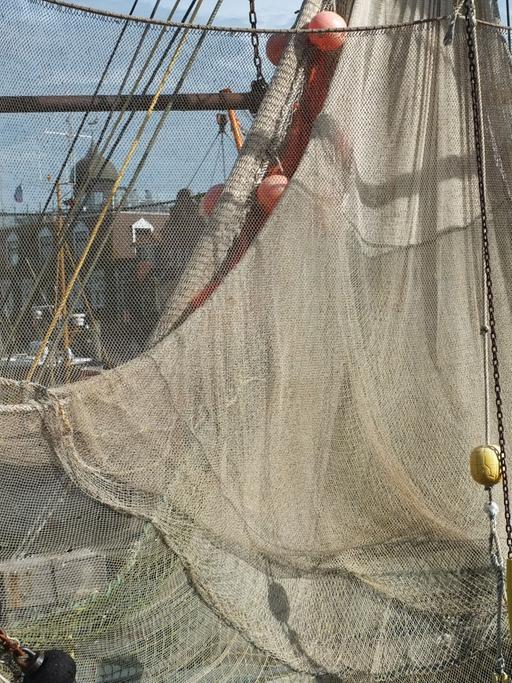 Ein Fangnetz ist auf einem Fischkutter aufgehängt.
