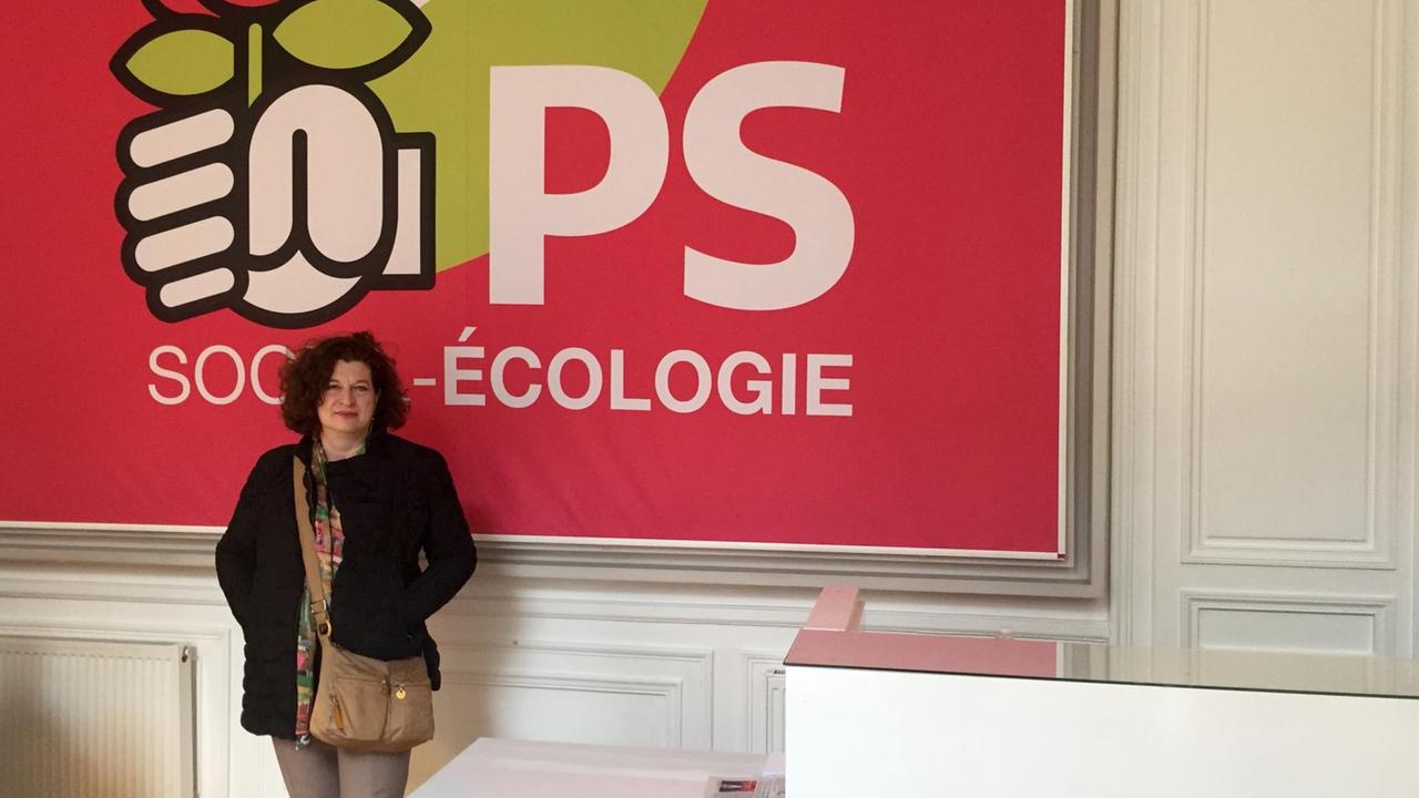 Elisabeth Humbert-Dorfmüller steht im langjährigen PS-Hauptsitz in Paris vor einem Partei-Plakat