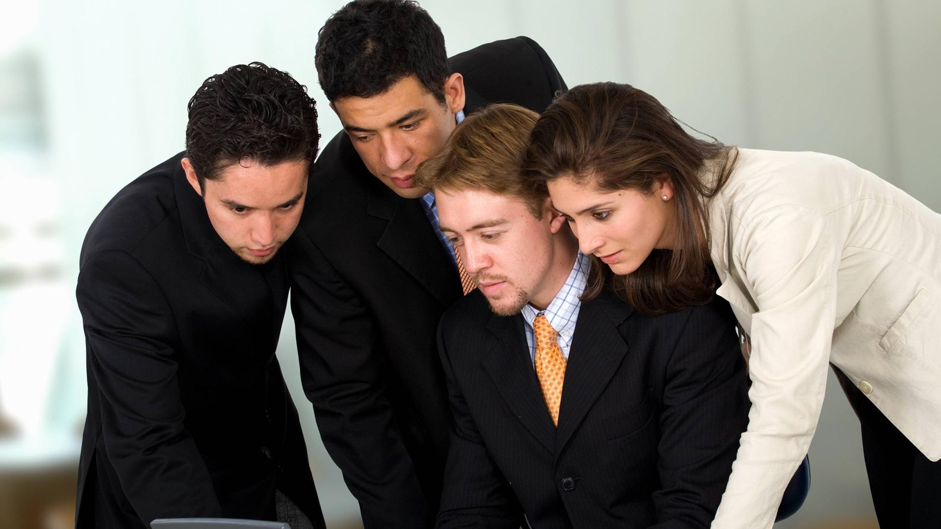 Ein Mann und eine Frau in Business-Look beugen sich gemeinsam über einen Laptop-Computer Ein Mann und eine Frau in Business-Look beugen sich gemeinsam über einen Laptop-Computer