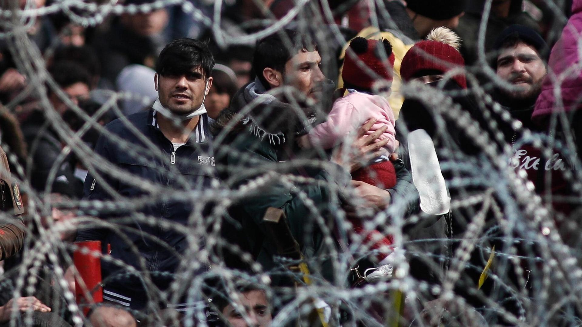 Migranten stehen am 2. März 2020 an der Grenze zwischen Griechenland und der Türkei an einem Stacheldrahtzaun.