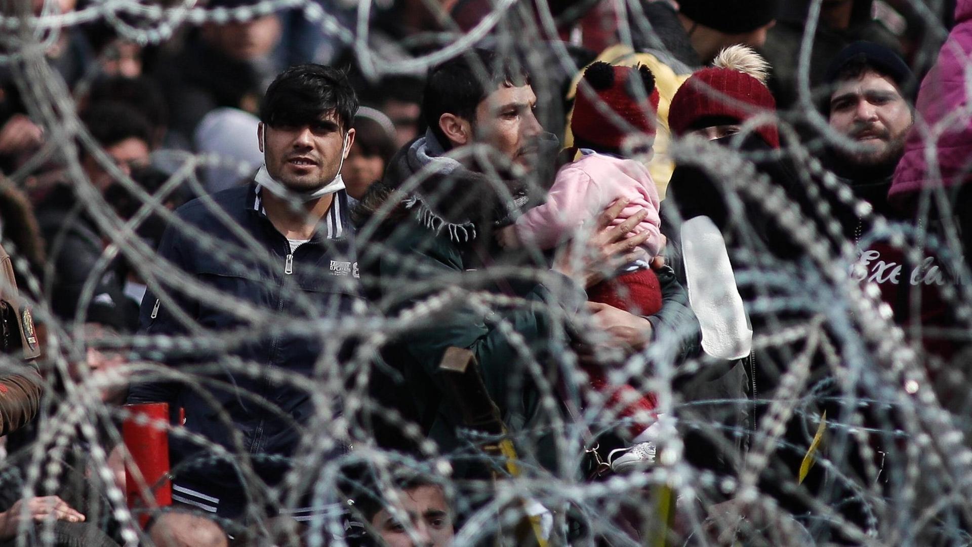 Migranten stehen am 2. März 2020 an der Grenze zwischen Griechenland und der Türkei an einem Stacheldrahtzaun. Migranten stehen am 2. März 2020 an der Grenze zwischen Griechenland und der Türkei an einem Stacheldrahtzaun.