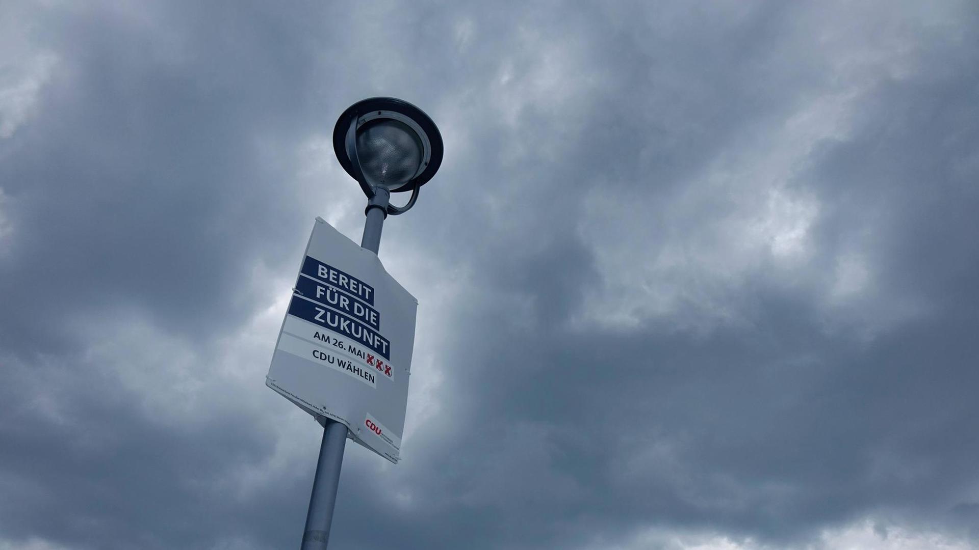 Ein Wahlplakat der CDU an einem Laternenpfahl vor Himmel mit dunklen Wolken. Ein Wahlplakat der CDU an einem Laternenpfahl vor Himmel mit dunklen Wolken.