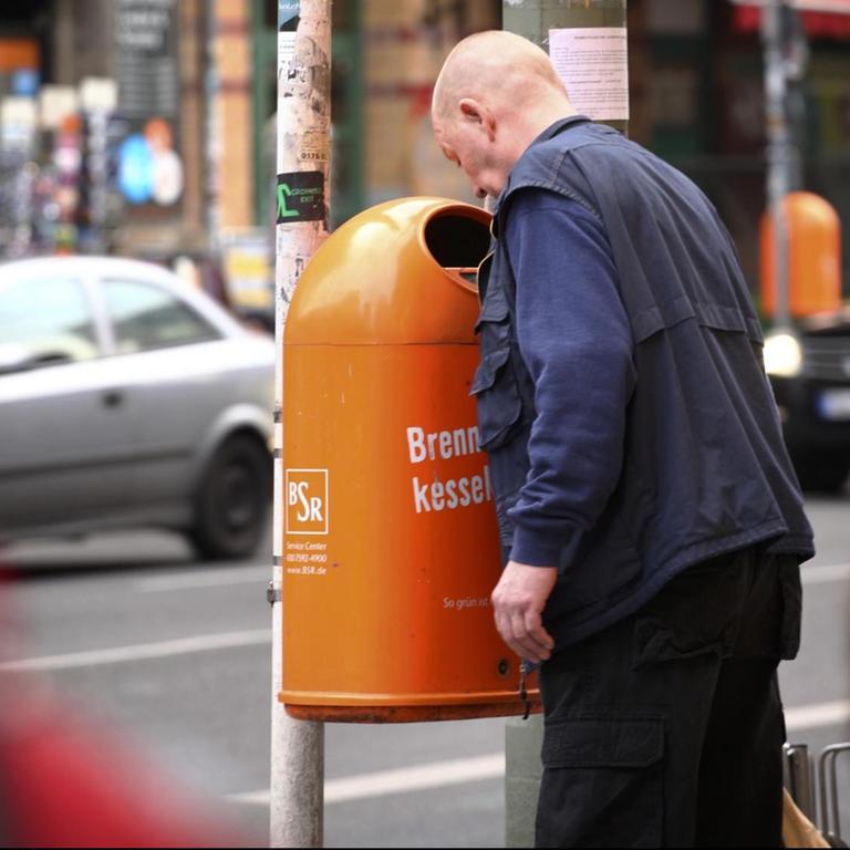 Ein Mann sucht in Berlin in einem Papierkorb nach Pfandflaschen oder Pfanddosen (Symbolbild)