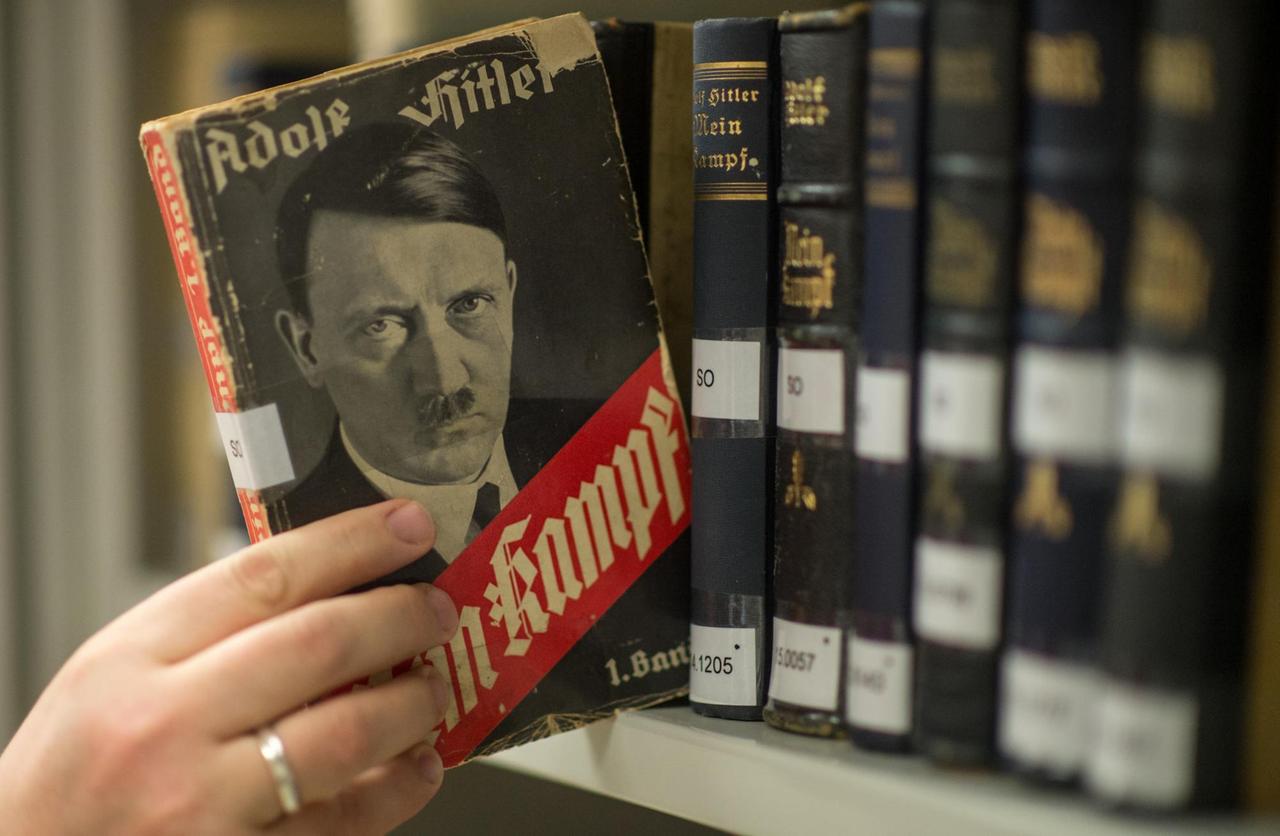 Man sieht, wie jemand eine Ausgabe von Hitlers "Mein Kampf" aus dem Jahr 1933 aus dem Regal zieht. Man sieht, wie jemand eine Ausgabe von Hitlers "Mein Kampf" aus dem Jahr 1933 aus dem Regal zieht.