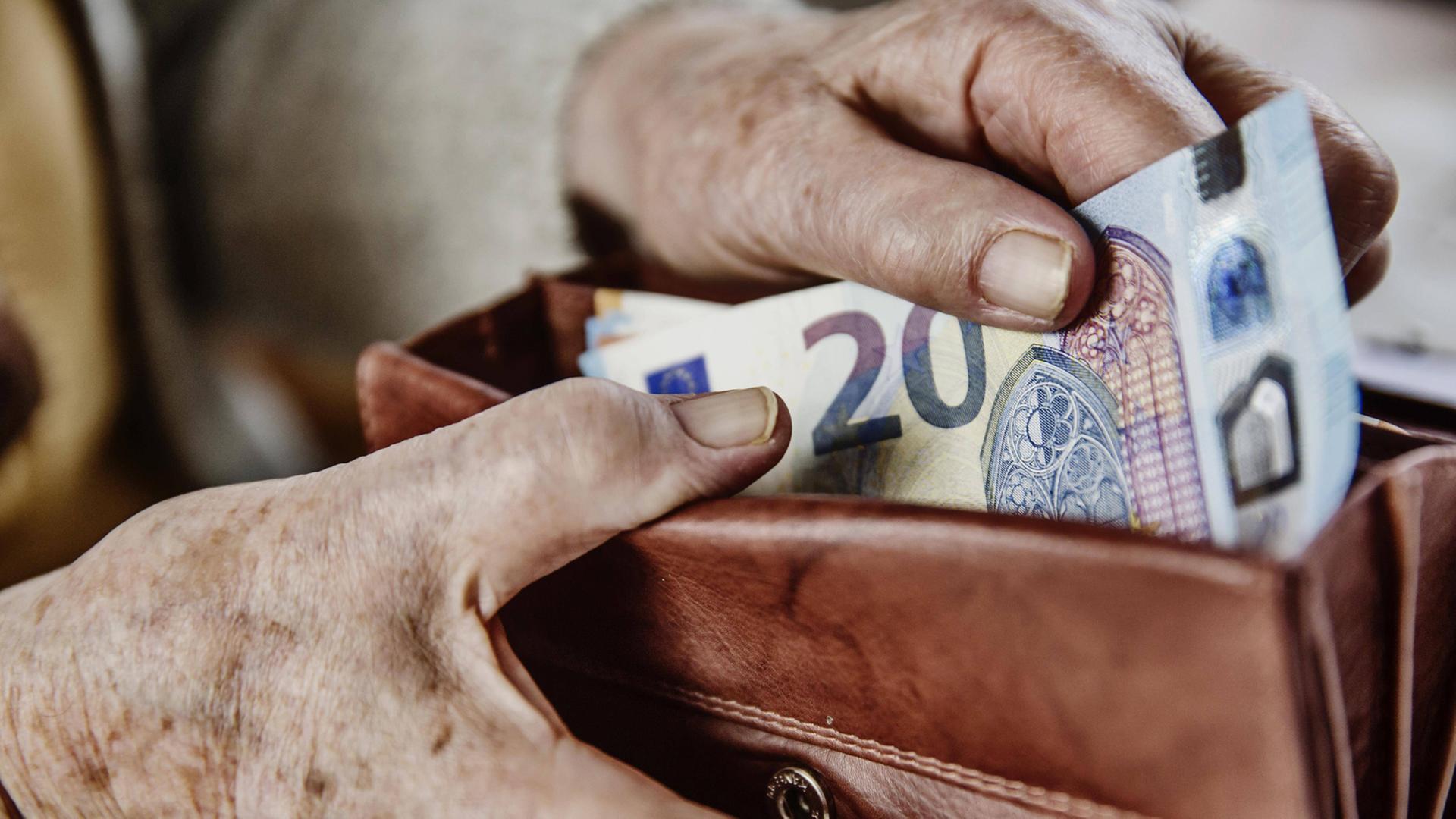 Eine Seniorin zieht einen 20 Euro Schein aus ihrem Portemonnaie.