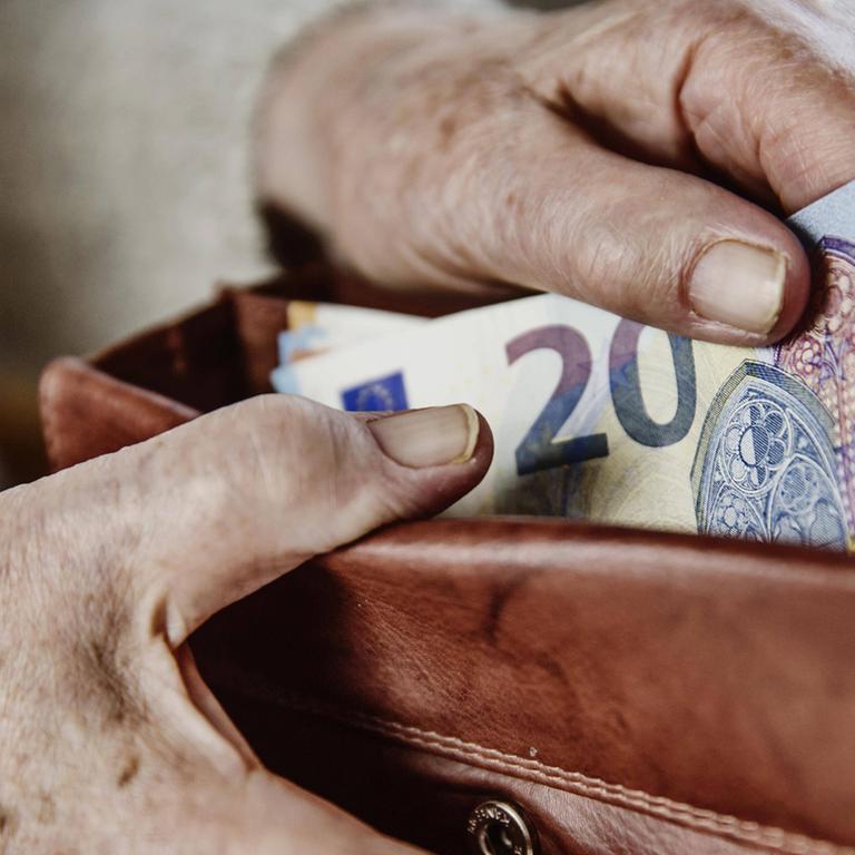 Eine Seniorin zieht einen 20 Euro Schein aus ihrem Portemonnaie.