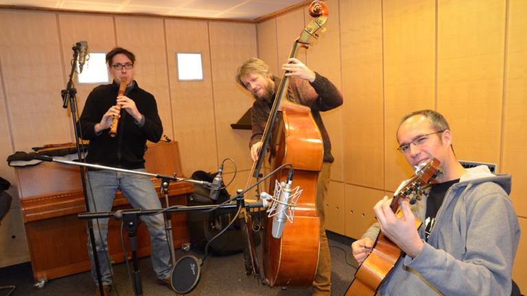 Auf dem Bild ist das Musiktrio "Wildes Holz" zu sehen: Tobias Reisige (links mit Mütze) auf der Flöte, in der Mitte Markus Conrads am Kontrabass und rechts (sitzend) Anto Karaula an der Gitarre. Auf dem Bild ist das Musiktrio "Wildes Holz" zu sehen: Tobias Reisige (links mit Mütze) auf der Flöte, in der Mitte Markus Conrads am Kontrabass und rechts (sitzend) Anto Karaula an der Gitarre.