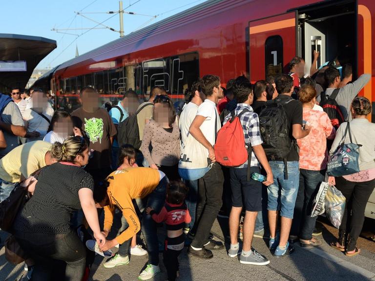 Eine Flüchtlingsmenge drängt sich vor der offenen Zugtür.