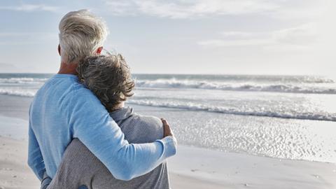 Ein älteres Paar umarmt sich am Strand.