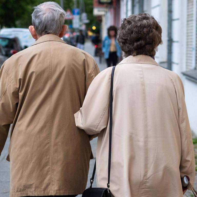 Ein älteres Ehepar läuft untergehakt durch Berlin