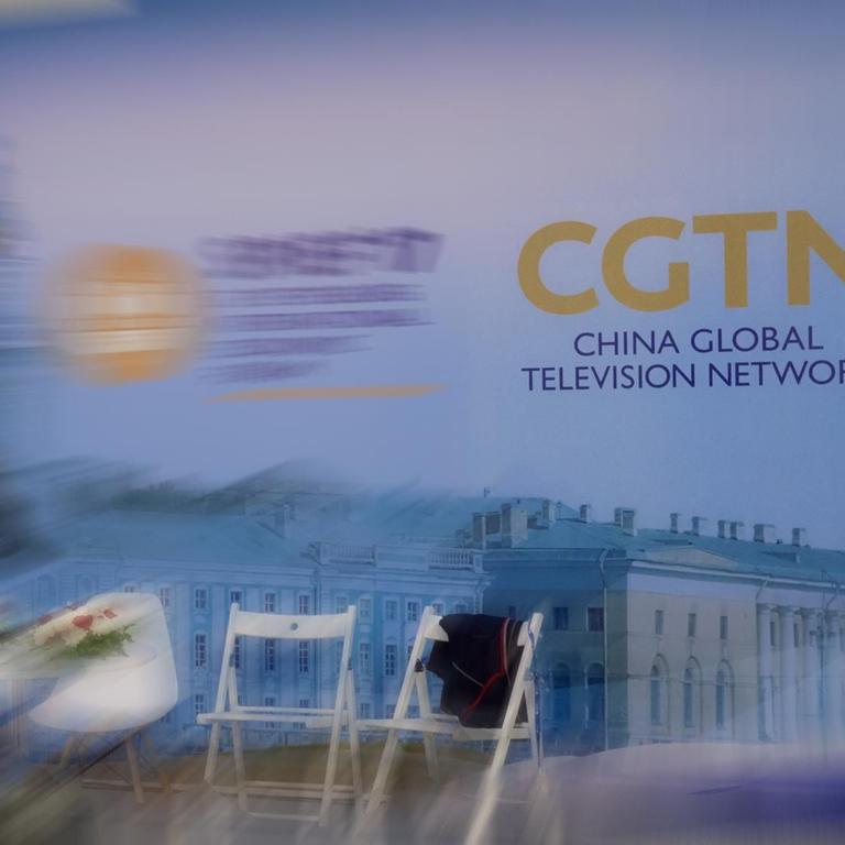 Mehrere Stühle stehen für eine Diskussionsrunde bereit. Im Hintergrund das Logo des staatlichen chinesischen Nachrichtensenders CGTN