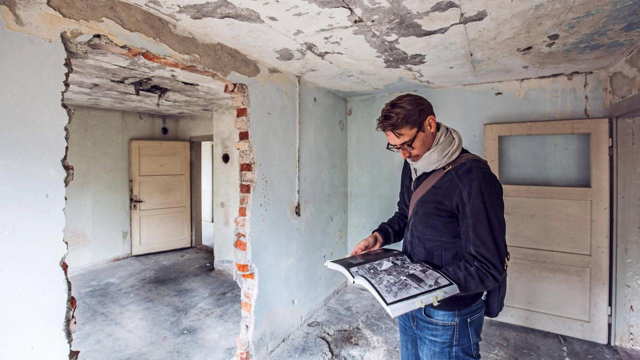 Dr. Paul-Moritz Rabe, Wissenschaftlicher Mitarbeiter des NS-Dokumentationszentrum, blättert in einem Buch, bei der Begehung von Baracke 5, auf dem Gelände des Zwangsarbeiterlagers München Neuaubing. Dr. Paul-Moritz Rabe, Wissenschaftlicher Mitarbeiter des NS-Dokumentationszentrum, blättert in einem Buch, bei der Begehung von Baracke 5, auf dem Gelände des Zwangsarbeiterlagers München Neuaubing.