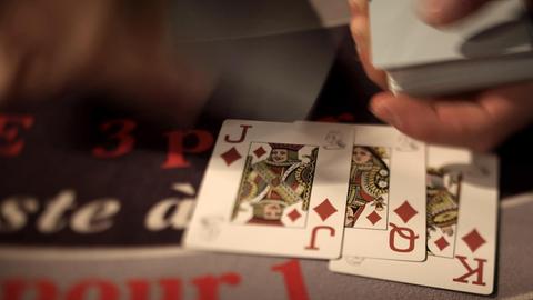 Kartenspieler legen ihr Blatt auf den Tisch beim Black Jack.