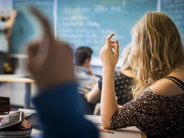 Schüler melden sich während einer Unterrichtsstunde in einer Gesamtschule.