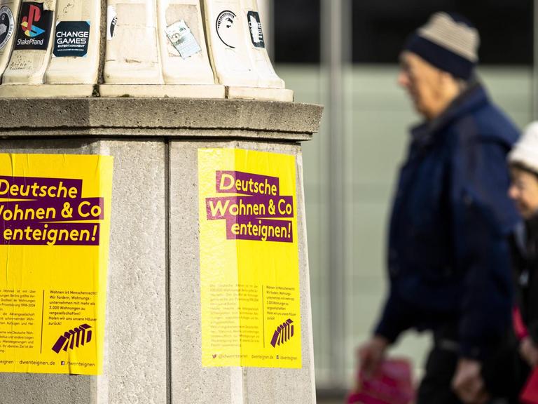 Protestplakate gegen Deutsche Wohnen und Passanten in der Karl-Marx-Allee in Berlin.