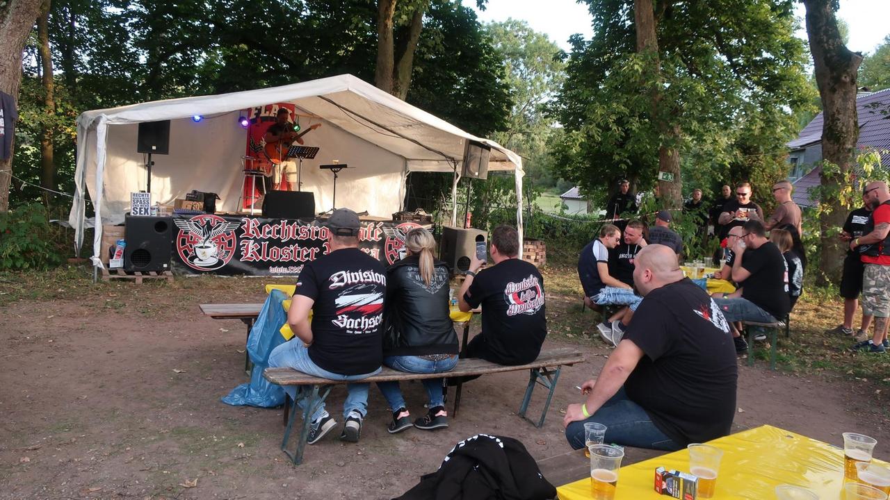 Vor einer kleinen Bühne sitzen die Rechten auf Bierbänken. Vor einer kleinen Bühne sitzen die Rechten auf Bierbänken.
