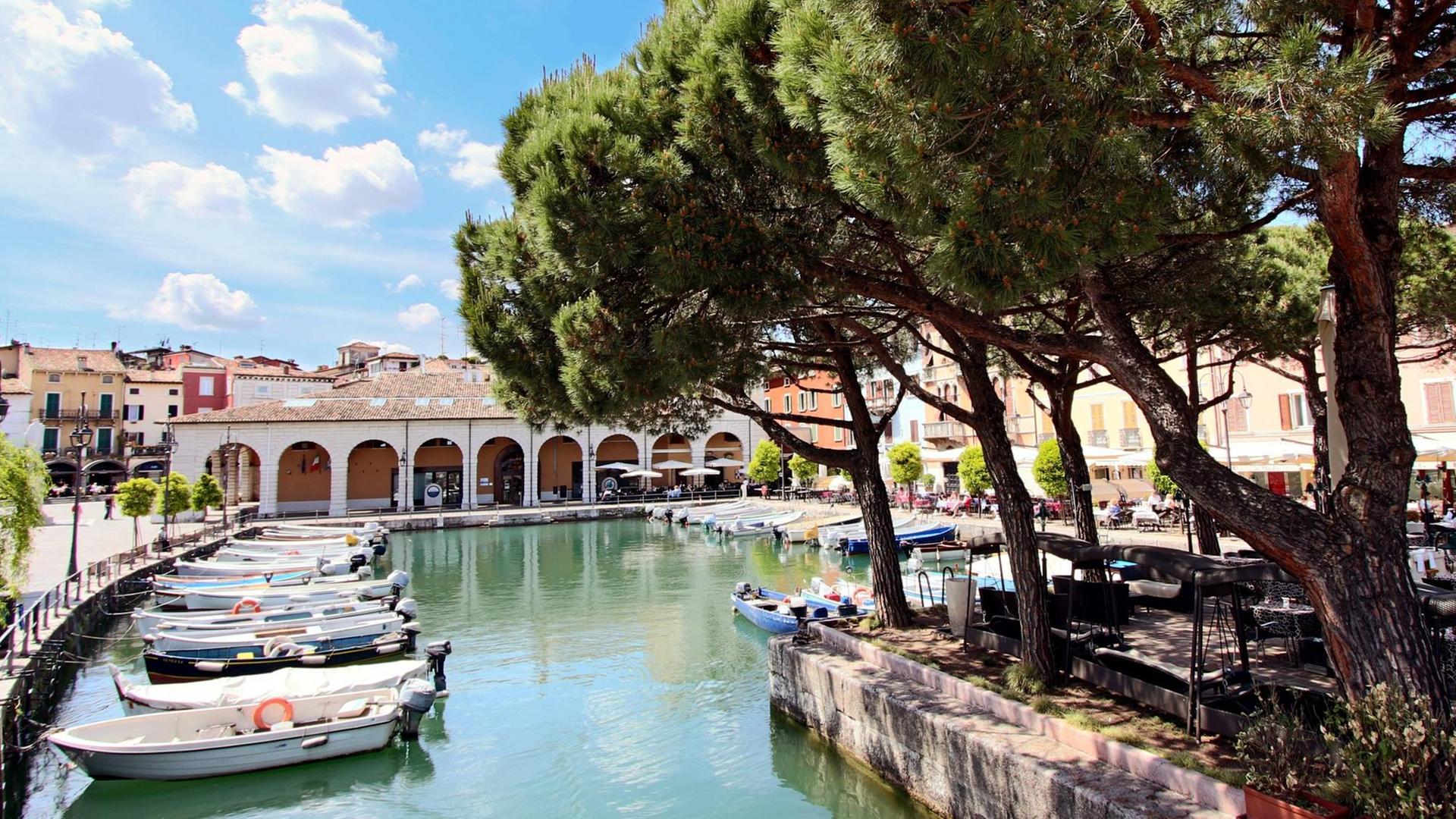 Uferpromenade mit Booten im historischen Hafen von Desenzano am Lago di Garda, Gardasee, Provinz Brescia, Region Lombardei.