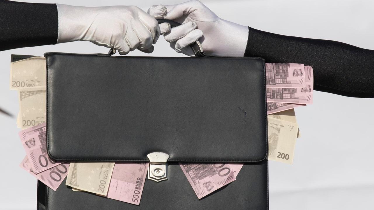 Eine Tasche mit heraushängenden Geldscheinen geht von einer Hand in die andere. Eine Tasche mit heraushängenden Geldscheinen geht von einer Hand in die andere.
