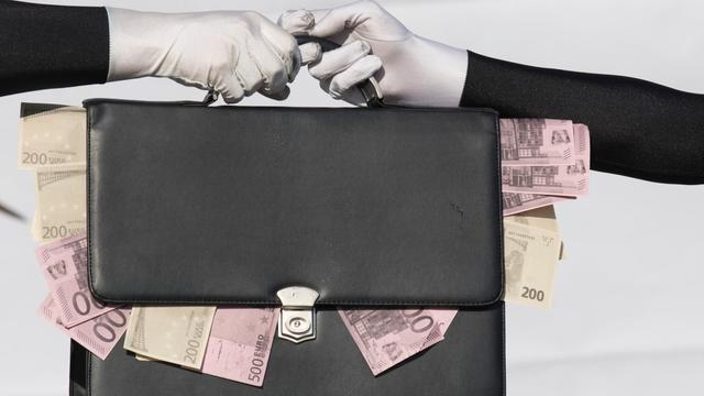 Eine Tasche mit heraushängenden Geldscheinen geht von einer Hand in die andere.
