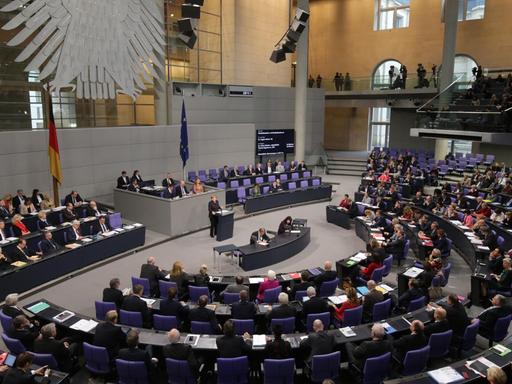 Der Blick auf das gut besetzte Plenum des Bundestages, am Rednerpult Kanzlerin Angela Merkel.