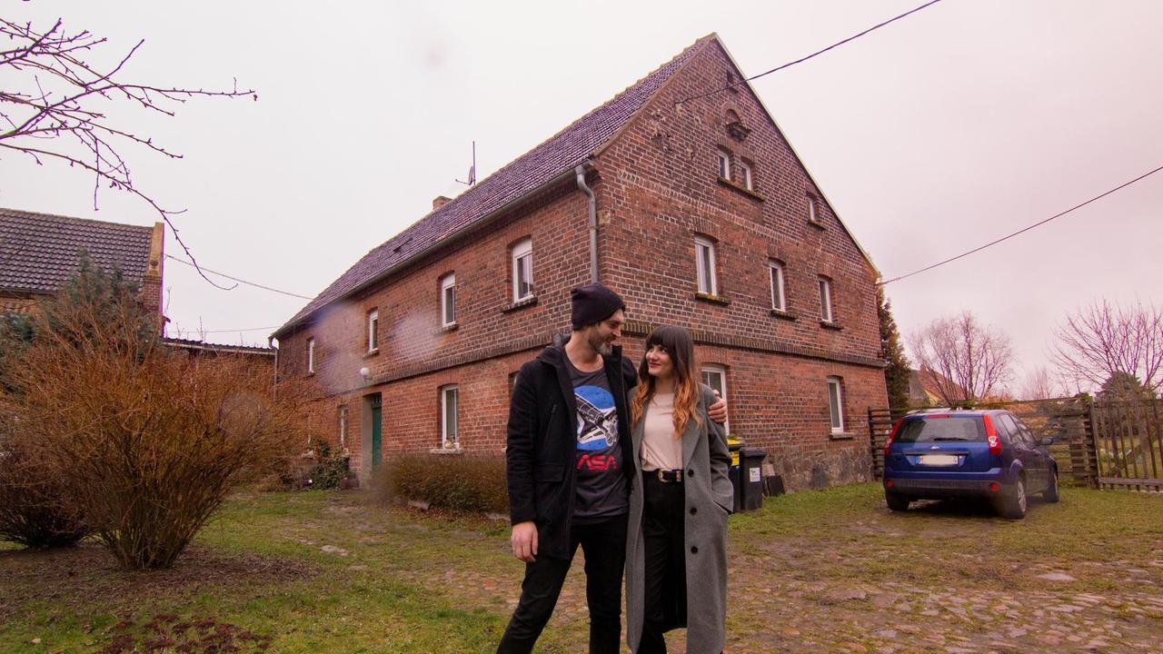 Ein Paar steht vor vor einem alten Bauernhaus. Ein Paar steht vor vor einem alten Bauernhaus.
