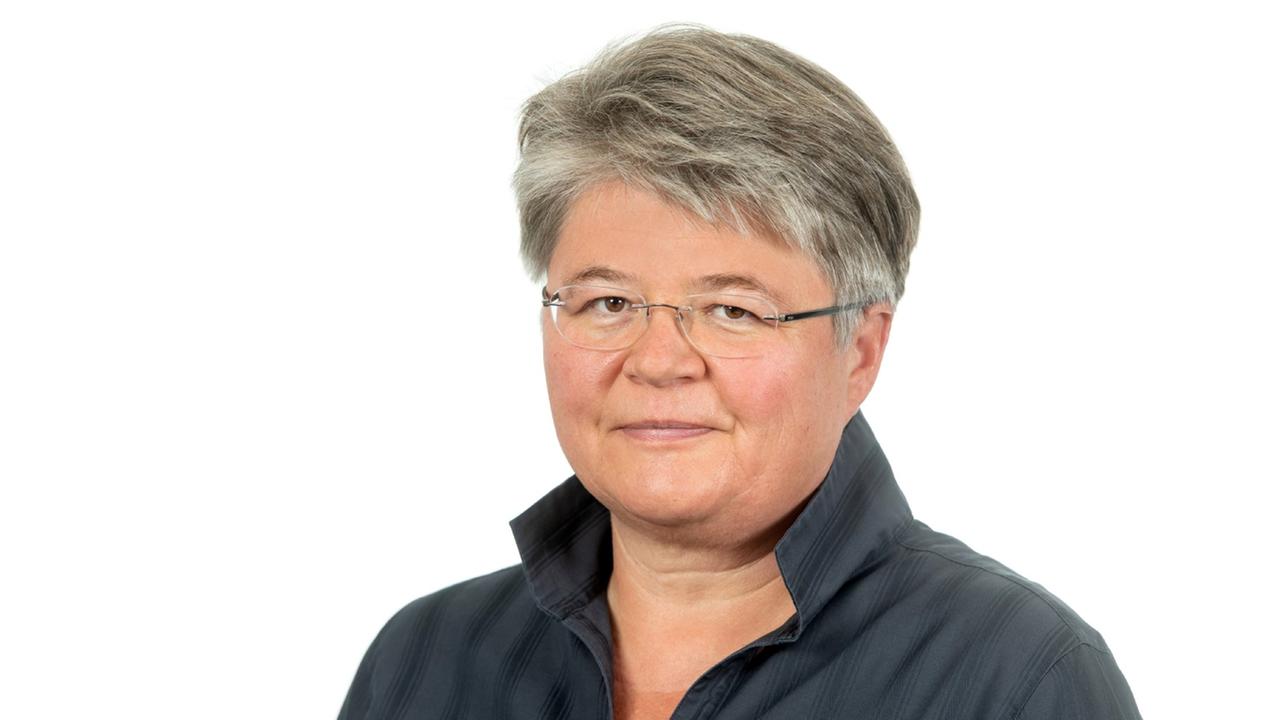 Porträt von Friederike Sittler, die vor neutralem weißem Hintergrund in die Kamera lächelt. Porträt von Friederike Sittler, die vor neutralem weißem Hintergrund in die Kamera lächelt.