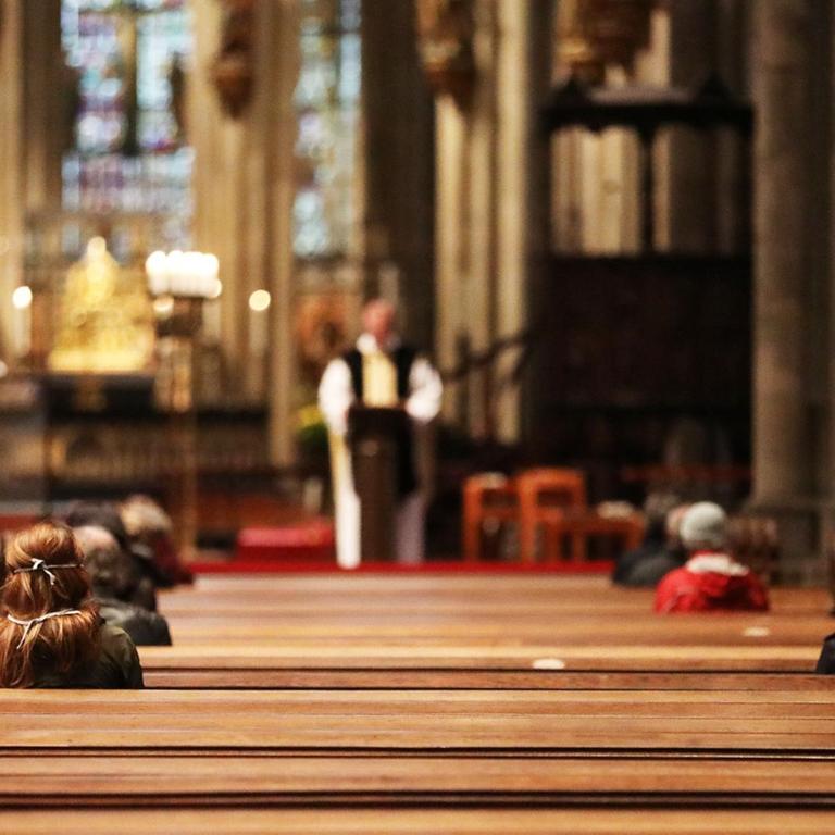 Gläubige sitzen während eines Gottesdienstes in den Sitzreihen im Kölner.