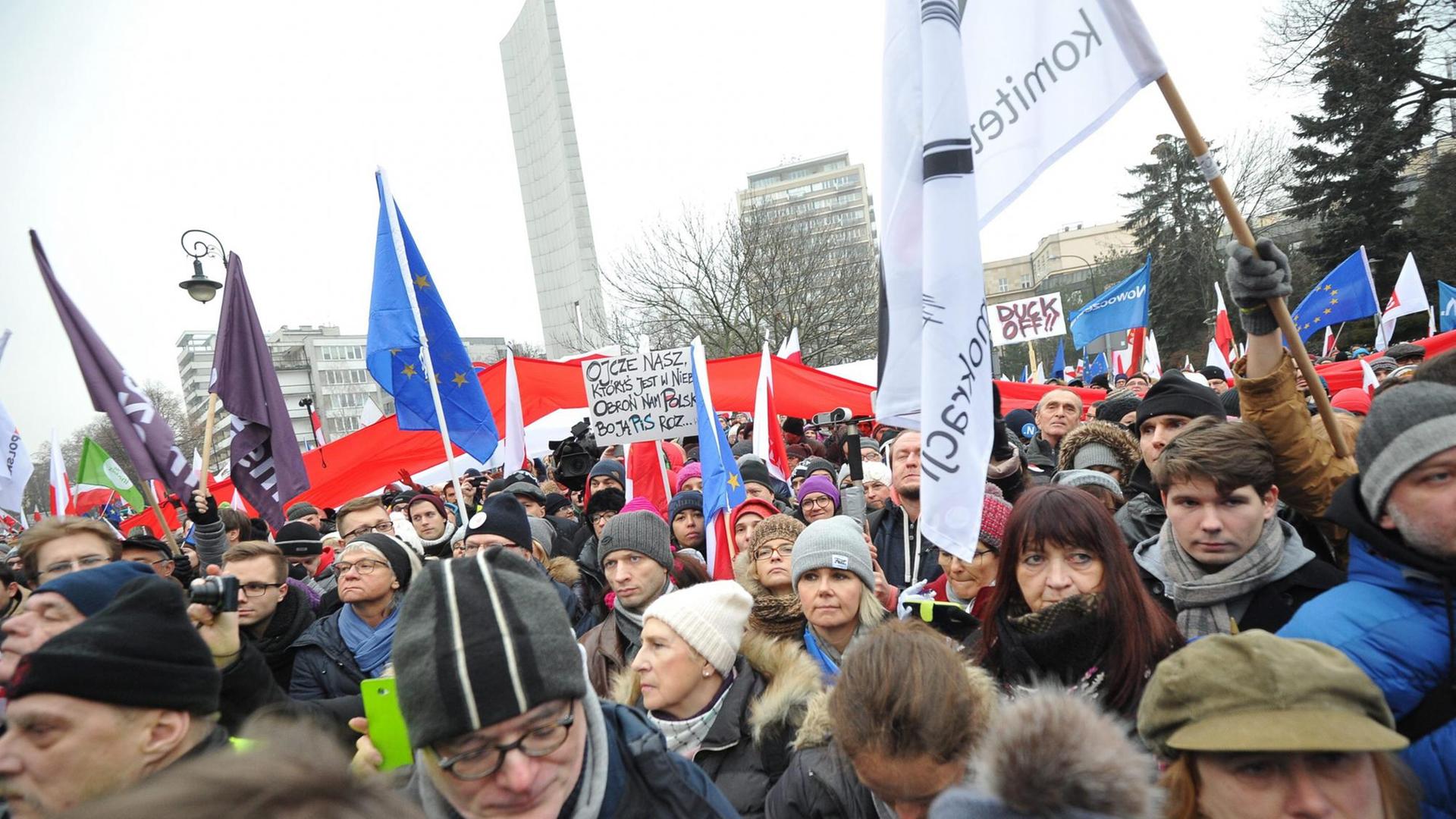 Eine Menschenmenge vor dem Parlamentsgebäude in Warschau hält Banner und Fahnen in die Höhe. Eine Menschenmenge vor dem Parlamentsgebäude in Warschau hält Banner und Fahnen in die Höhe.