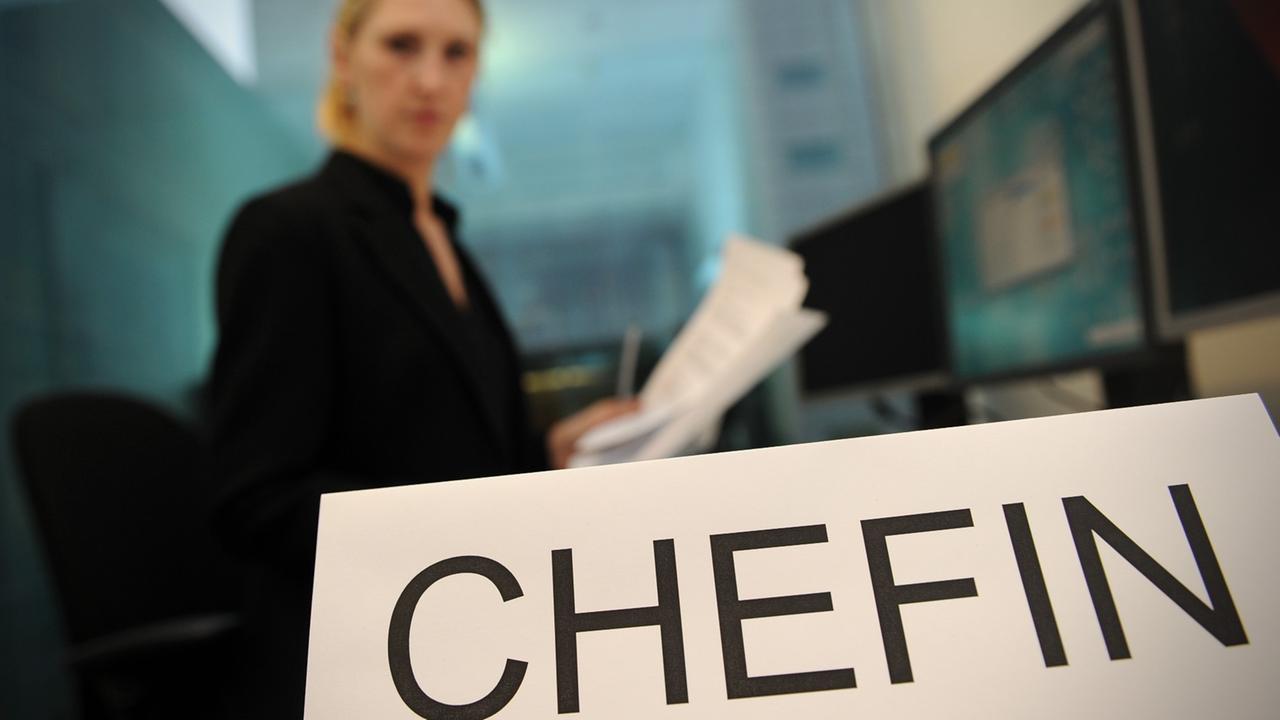 Eine Frau sitzt an einem Arbeitsplatz, vor ihr steht das Schild mit der Aufschrift "Chefin" Eine Frau sitzt an einem Arbeitsplatz, vor ihr steht das Schild mit der Aufschrift "Chefin"