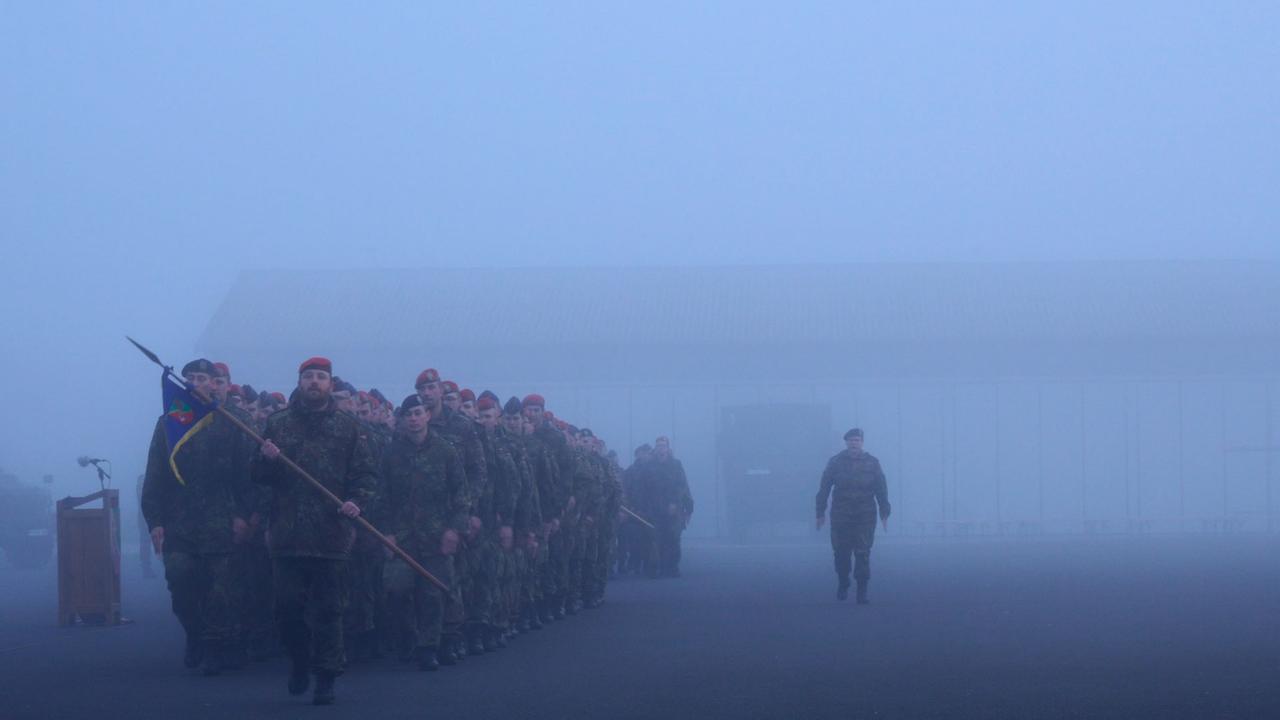 Eine Gruppe Soldaten steht auf einem vernebelten Hof in Reih und Glied. Eine Gruppe Soldaten steht auf einem vernebelten Hof in Reih und Glied.