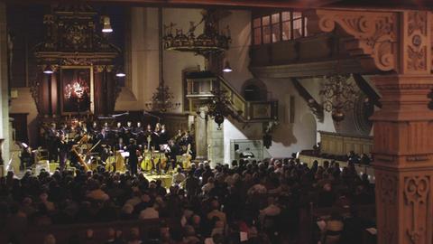 Blick in einen Kirchenraum, in dessen Altarbereich ein Orchester mit historischen Instrumenten spielt.