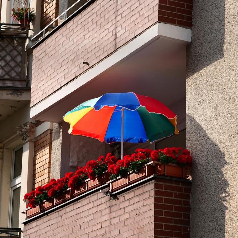 Ein bunter Sonnenschirm steht auf dem Balkon eines Mietshauses aus den 1920er/1930er im Stadtteil Steglitz in Berlin am 12.06.2020. Foto: Wolfram Steinberg/dpa | Verwendung weltweit