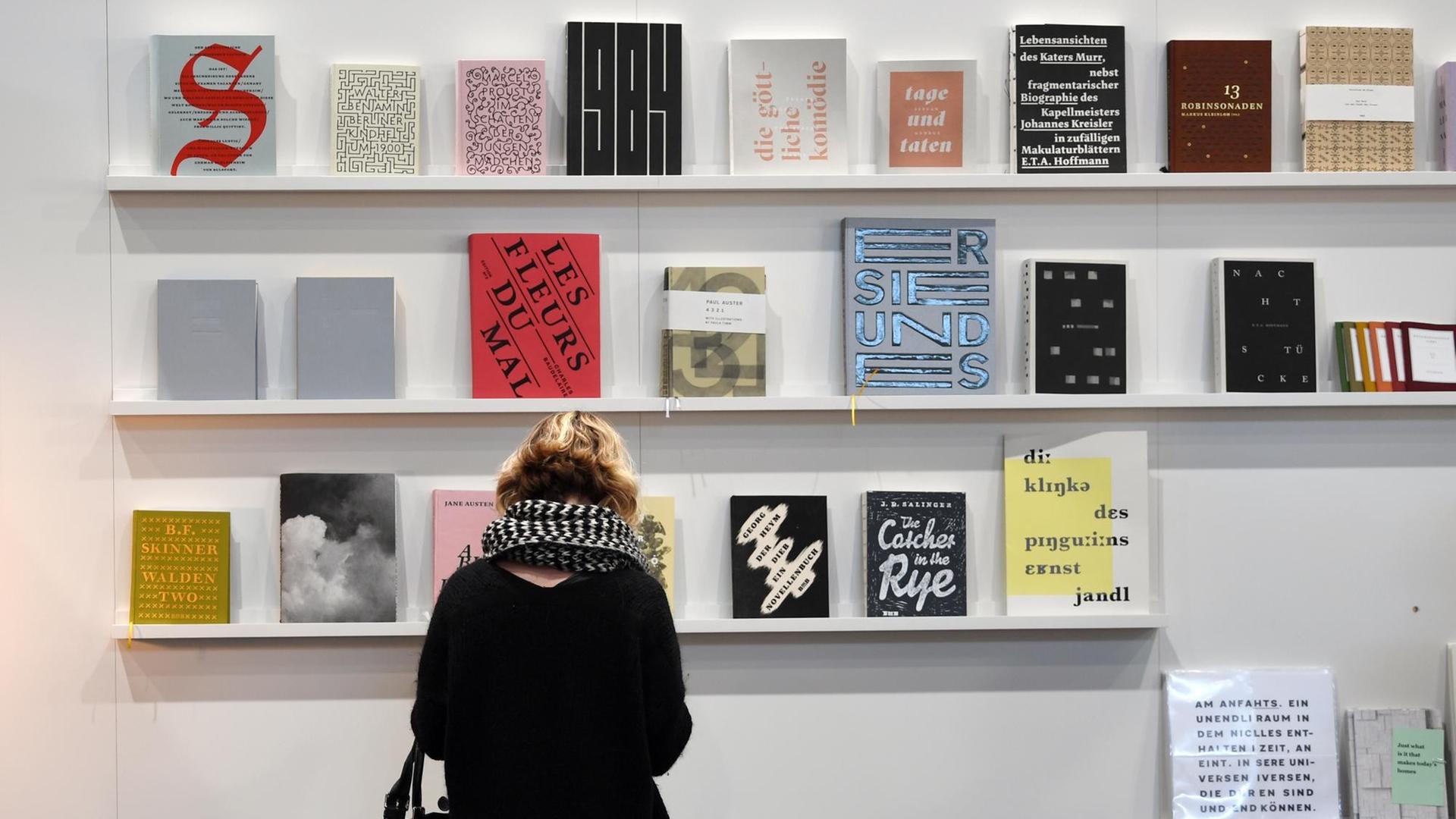 Eine Besucherin der Leipziger Buchmesse 2019 blättert in einem Buch am Stand der Muthesius Kunsthochschule Kiel. Eine Besucherin der Leipziger Buchmesse 2019 blättert in einem Buch am Stand der Muthesius Kunsthochschule Kiel.