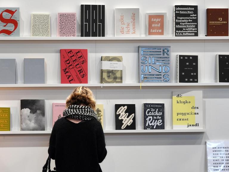 Eine Besucherin der Leipziger Buchmesse 2019 blättert in einem Buch am Stand der Muthesius Kunsthochschule Kiel.