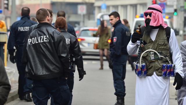 Ein als Terrorist verkleideter Karnevalist mit einem Gürtel aus Energydrinks, der an einen Sprengstoffgürtel erinnert