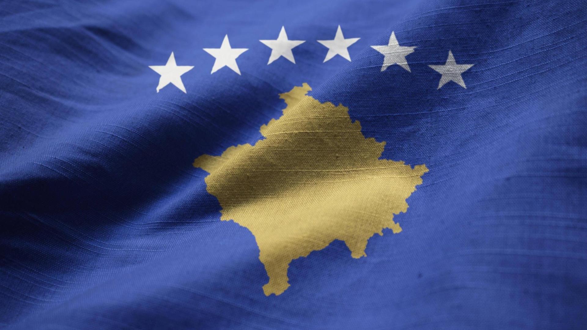 Die Flagge zeigt auf blauem Hintergrund den Umriss des Kosovo. Darüber sind sechs Sterne im Halbkreis platziert.