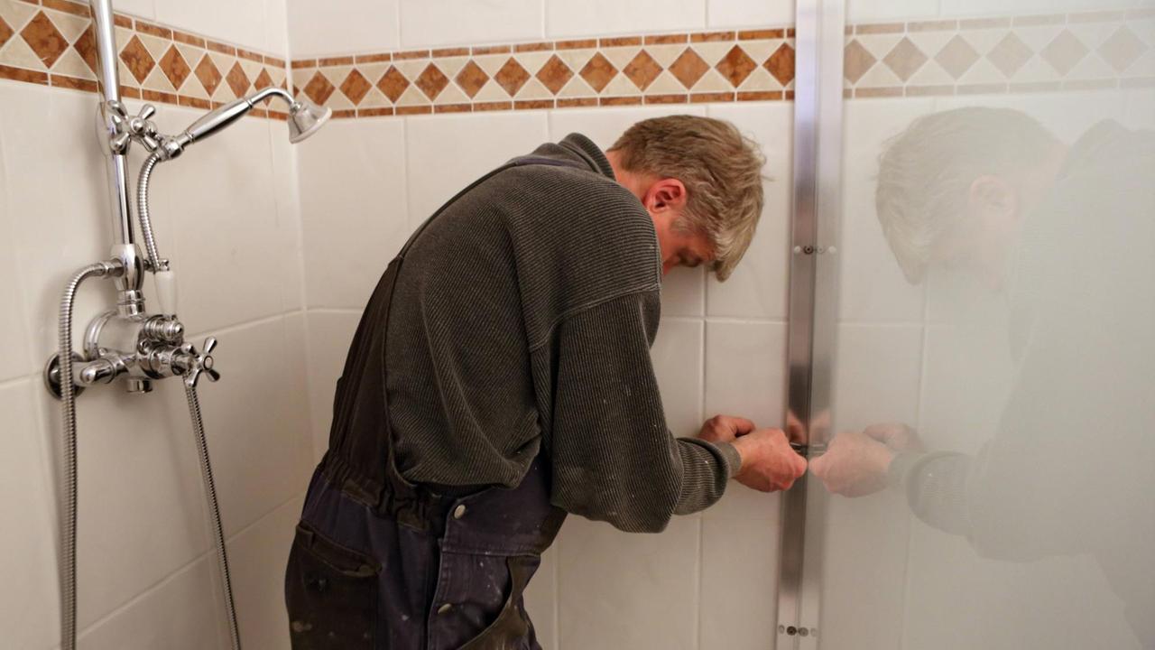 Monteur installiert eine Duschwand im Badezimmer. Monteur installiert eine Duschwand im Badezimmer.