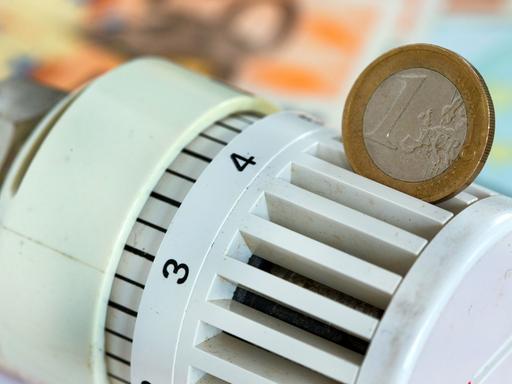 Eine Euromünze steckt in einem Heizungsthermostat.