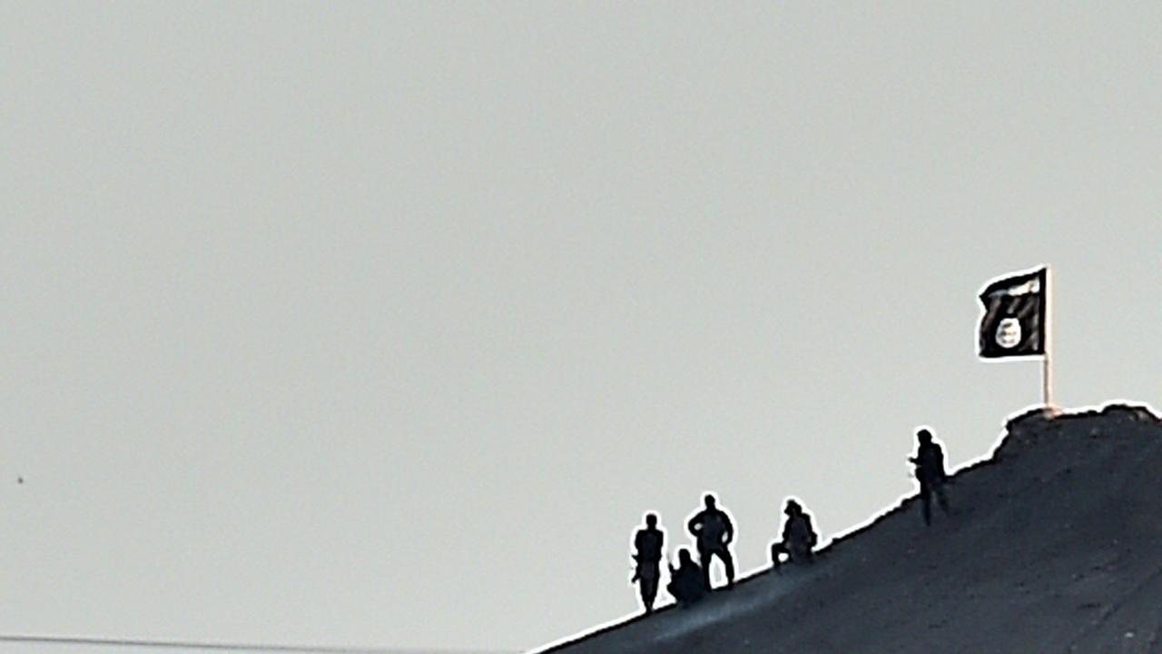 Mutmaßliche Kämpfer des Islamischen Staates hissen die Flagge der Miliz auf einem Hügel bei Kobane in Syrien. Mutmaßliche Kämpfer des Islamischen Staates hissen die Flagge der Miliz auf einem Hügel bei Kobane in Syrien.