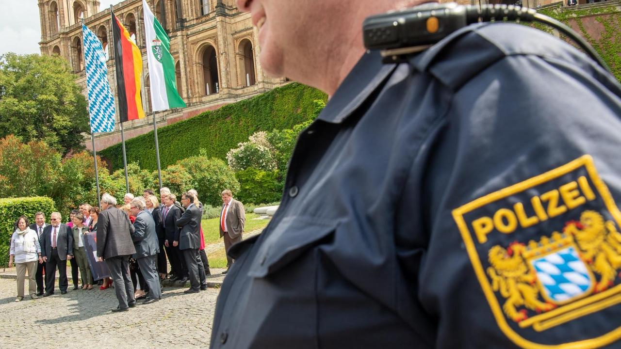 15.05.2018, Bayern, München. Mitglieder der SPD-Landtagsfraktion nehmen vor Beginn der Plenarsitzung im Landtag an einer Plakat-Aktion gegen das Polizeiaufgabengesetz (PAG) teil und werden von einem Polizisten in Uniform beobachtet. Das PAG soll am späten Abend im bayerischen Landtag verabschiedet werden. Foto: Peter Kneffel/dpa | Verwendung weltweit 15.05.2018, Bayern, München. Mitglieder der SPD-Landtagsfraktion nehmen vor Beginn der Plenarsitzung im Landtag an einer Plakat-Aktion gegen das Polizeiaufgabengesetz (PAG) teil und werden von einem Polizisten in Uniform beobachtet. Das PAG soll am späten Abend im bayerischen Landtag verabschiedet werden. Foto: Peter Kneffel/dpa | Verwendung weltweit