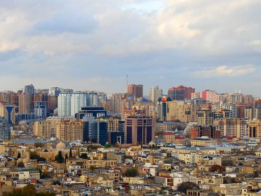 Die Altstadt der aserbaidschanischen Hauptstadt Baku mit Minaretten liegt vor dichtbebauten neuen Hochhäusern.
